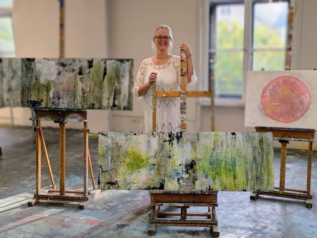Sabine Huber zwischen Arbeiten der abstrakten Naturmalerei.
